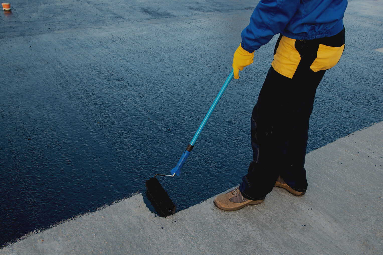 Worker applies bitumen mastic on the foundation